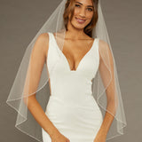 Fingertip Veil with Pearls and Sequins Woman wearing a wedding dress with a sheer veil against a neutral background