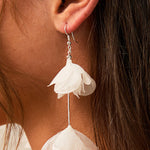 Light Ivory Organza Flower Earrings A close-up of a person's ear wearing a dangling earring with two layered ivory  fabric flower shapes hanging from silver hooks.