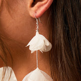 Light Ivory Organza Flower Earrings A close-up of a person's ear wearing a dangling earring with two layered ivory  fabric flower shapes hanging from silver hooks.
