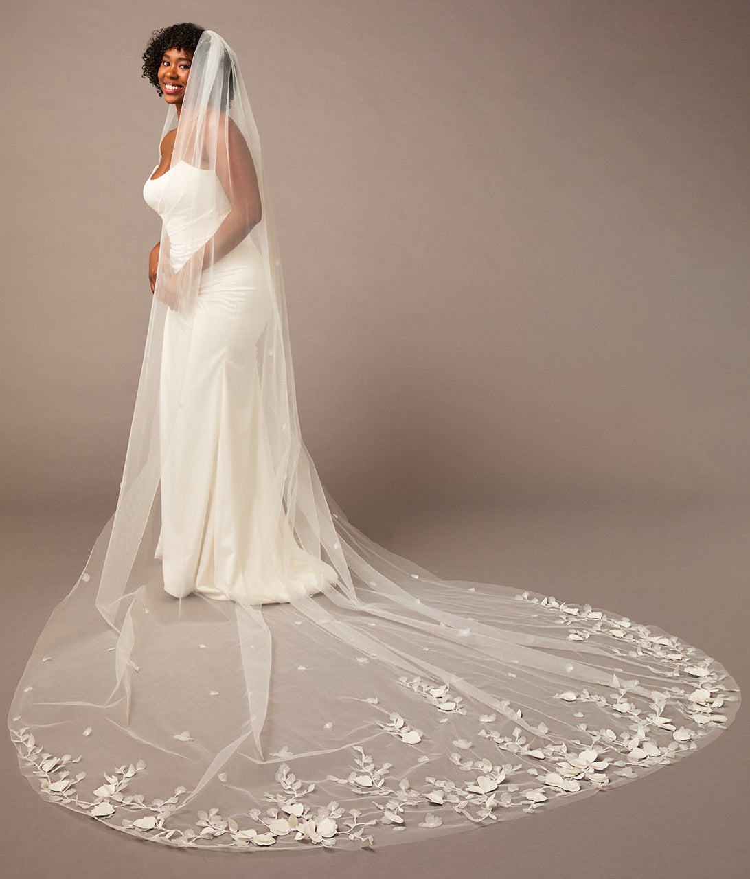 Woman wearing a white wedding dress with a long, floral-embellished veil on a brown background 3D Flowers and Leaves Bridal Royal Cathedral Veil