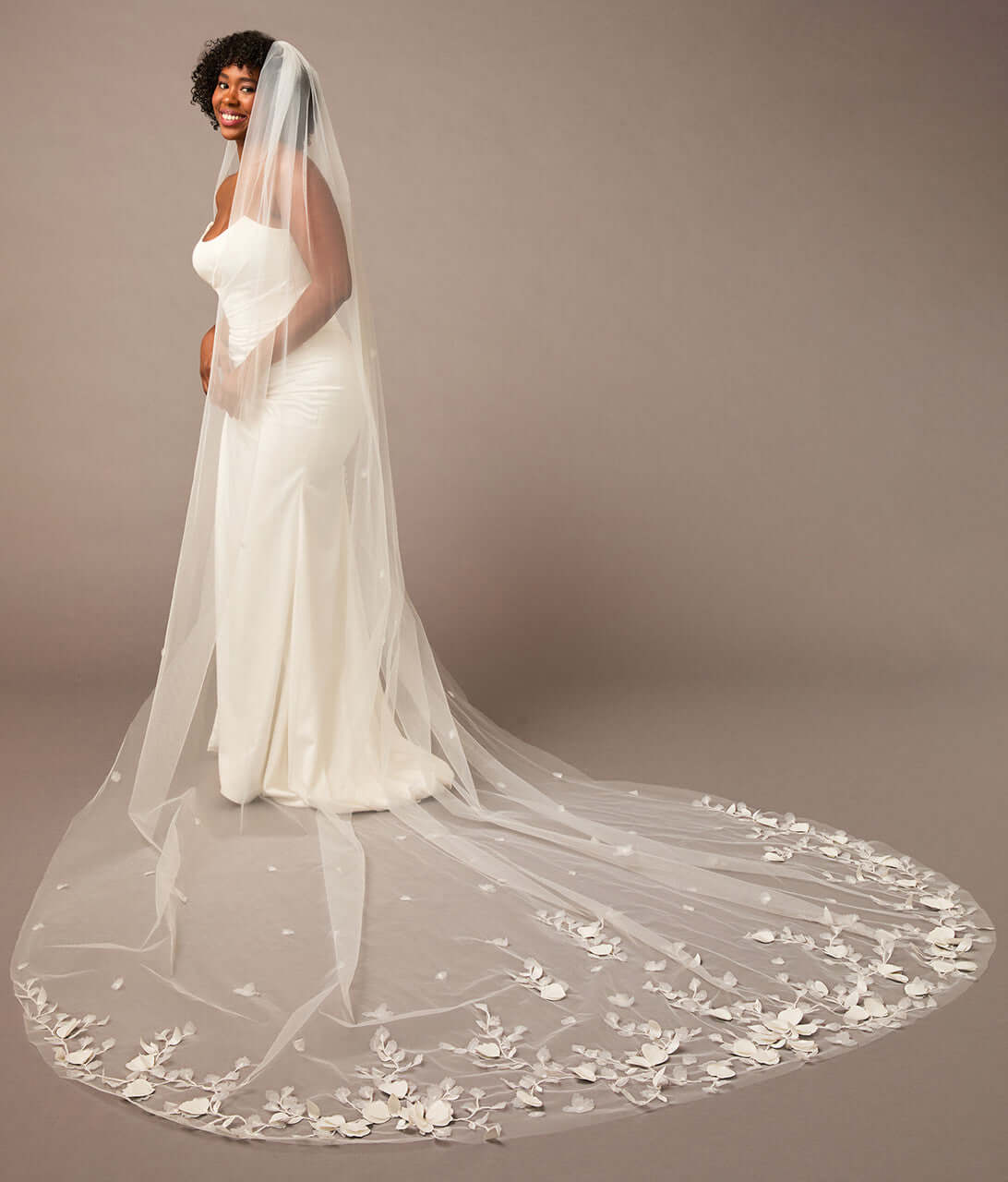 Woman wearing a white wedding dress with a long, floral-embellished veil on a brown background 3D Flowers and Leaves Bridal Royal Cathedral Veil