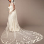 Woman wearing a white wedding dress with a long, floral-embellished veil on a brown background 3D Flowers and Leaves Bridal Royal Cathedral Veil