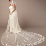 Woman wearing a white wedding dress with a long, floral-embellished veil on a brown background 3D Flowers and Leaves Bridal Royal Cathedral Veil