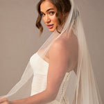 Woman wearing a white wedding dress with a long veil against a brown background Royal Cathedral Bridal Veil Floral Embroidered Lace - Cassandra Lynne