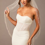 Pearl Wave Fingertip Bridal Veil Woman wearing a  strapless dress and veil against a neutral background