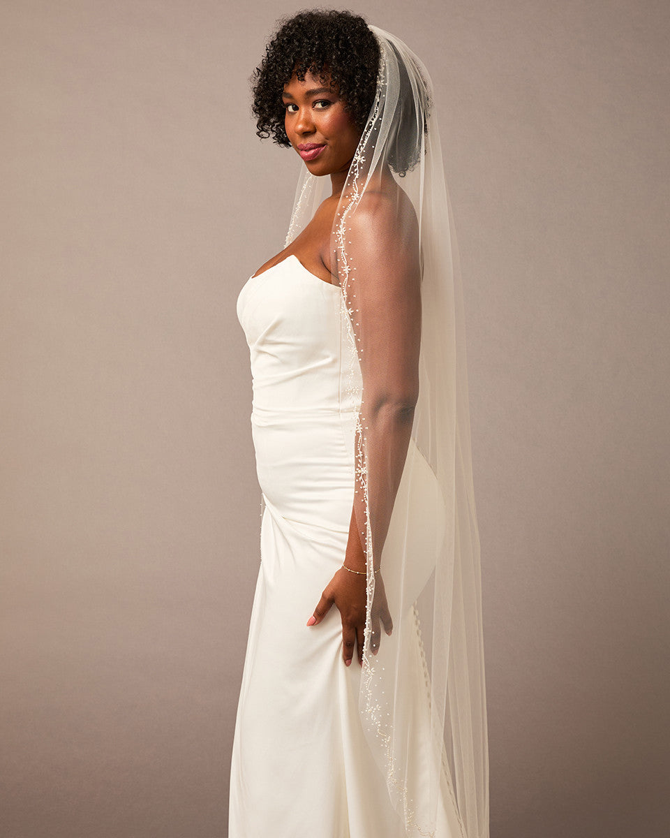 Pearl Wave Waltz Length Bridal Veil Woman wearing a wedding dress with a veil against a plain background