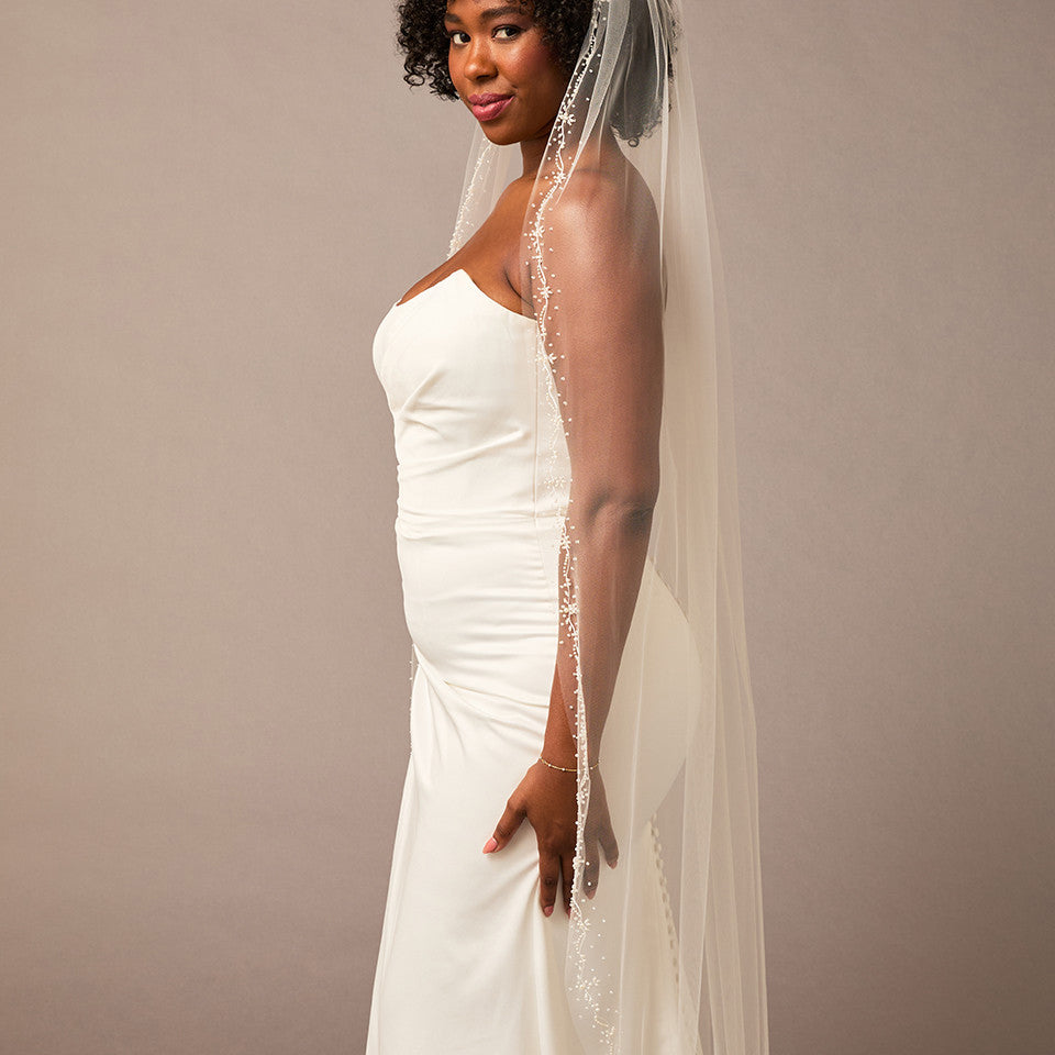 Pearl Wave Waltz Length Bridal Veil Woman wearing a wedding dress with a veil against a plain background