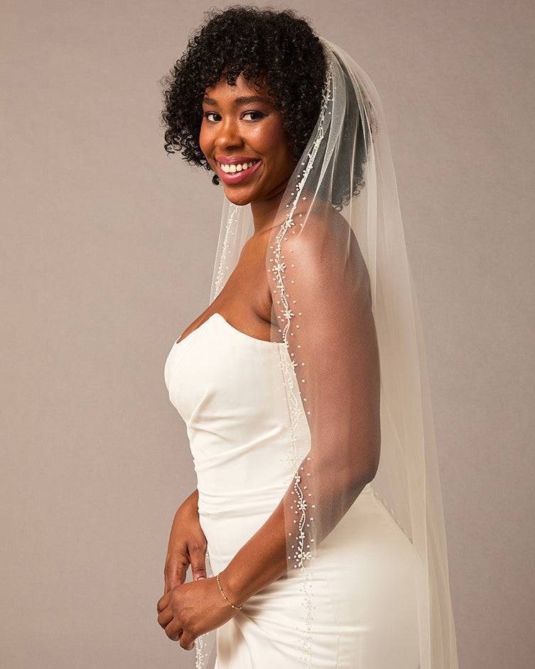 Pearl Wave Waltz Length Bridal Veil Woman wearing a wedding dress with a veil against a plain background