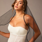 Woman wearing a dress with a black veil against a neutral background