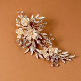 Porcelain Ivory Flowers and Crystals Bridal Clip A floral bridal hair claw clip featuring cream-colored faux flowers and silver-toned leaves, accented with clear rhinestones, displayed on a warm brown background.