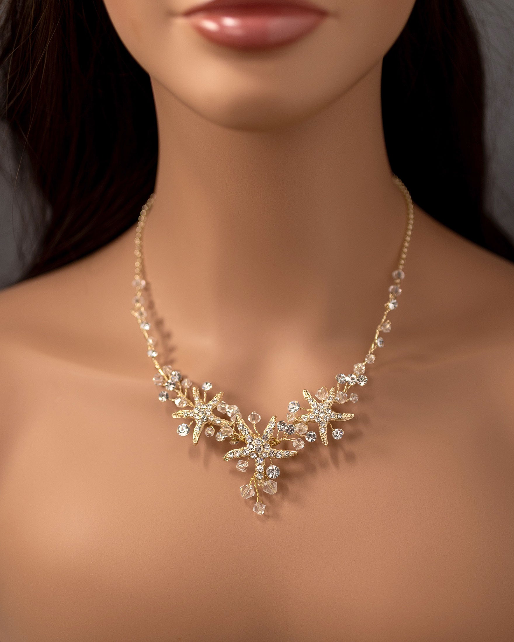 Three crystal covered starfish are surrounded by crystal stones and beads for a sparkly look. Matching bracelet here.