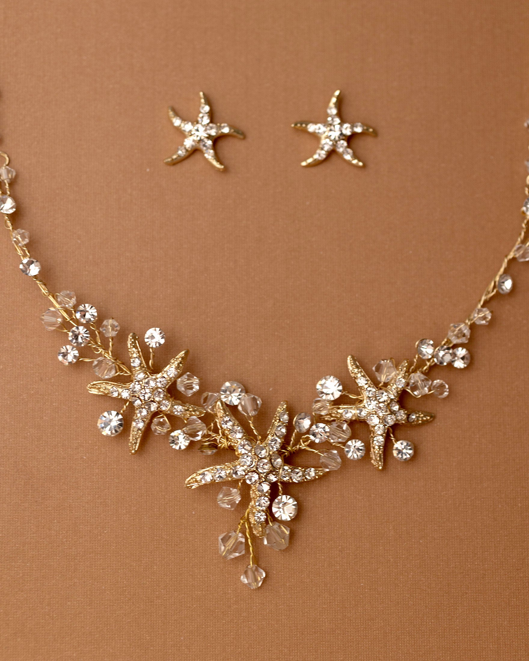 Three crystal covered starfish are surrounded by crystal stones and beads for a sparkly look. Matching bracelet here.