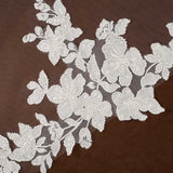 Royal Cathedral Veil with Flower Appliques and Sequins Cassandra Lynne - floral lace applique with embroidered flowers and leaves on a sheer mesh backing, displayed against a dark brown background.