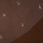 Bridal Veil with Crystal Raindrop Scatter A close-up of a brown textured fabric or material surface with a diagonal split and several small white hook-like details scattered across it.