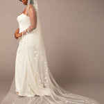 Cathedral Veil with Vine Appliques Woman wearing a wedding dress with a long veil against a brown background