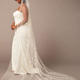 Cathedral Veil with Vine Appliques Woman wearing a wedding dress with a long veil against a brown background