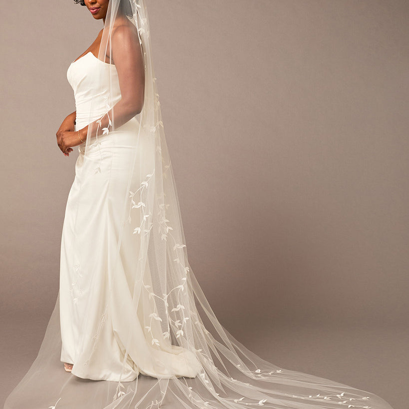 Cathedral Veil with Vine Appliques Woman wearing a wedding dress with a long veil against a brown background