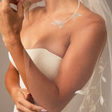 Cathedral Veil with Vine Appliques Close-up of a person wearing a white wedding dress with a floral veil.