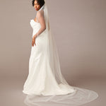Woman wearing a  wedding dress with a long veil on a plain background Fingertip Bridal Veil with Opaque Beads and Crystals