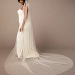 Royal Veil with Raindrop Scatter Woman wearing a wedding dress with a long veil against a plain background