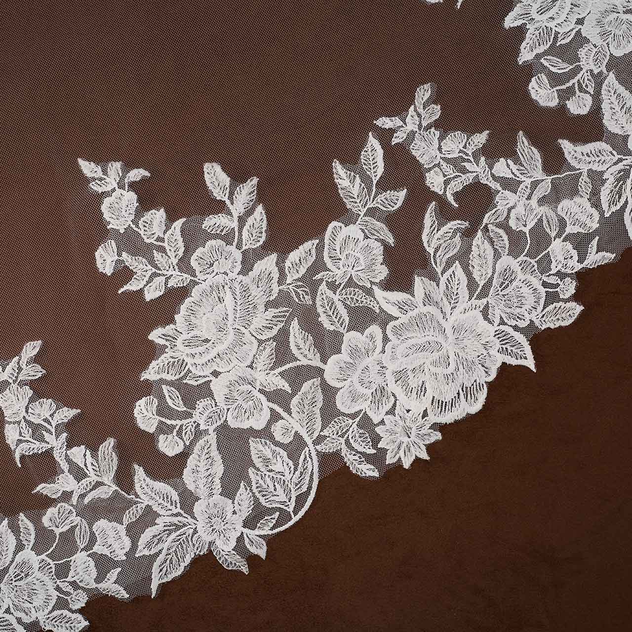 Rose Lace Royal Cathedral Bridal Veil Cassandra Lynne - floral lace trim with detailed rose motifs and leaves, laid diagonally across a solid dark brown background.