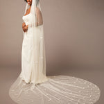 Royal Cathedral Veil of Luxe Tulle and Bows Woman wearing a long wedding veil against a plain background