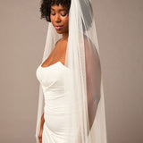 Royal Cathedral Veil of Luxe Tulle and Bows Woman wearing a wedding dress with a veil against a plain background