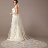 Cathedral Veil with Gold Sequined Dandelion Accents Woman wearing a wedding dress with a long veil against a brown background