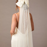Royal Cathedral Ivory Bow Wedding Veil Woman wearing a wedding dress with a long veil and large bow on a plain background