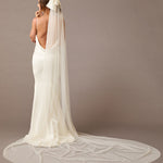 Royal Cathedral Ivory Bow Wedding Veil Woman wearing a long  wedding veil with a bow on a brown background