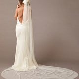 Royal Cathedral Ivory Bow Wedding Veil Woman wearing a long  wedding veil with a bow on a brown background