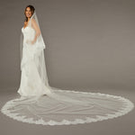 Two Layer Chantilly Lace Cathedral Bridal Veil Woman wearing a wedding dress with a long veil on a gray background