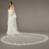 Two Layer Chantilly Lace Cathedral Bridal Veil Woman wearing a wedding dress with a long veil on a gray background