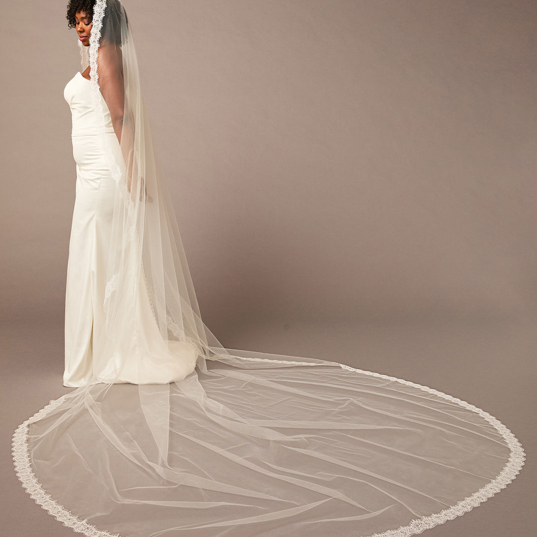 Double Eyelash Lace Cathedral Mantilla Veil Woman wearing a long white wedding veil against a plain background