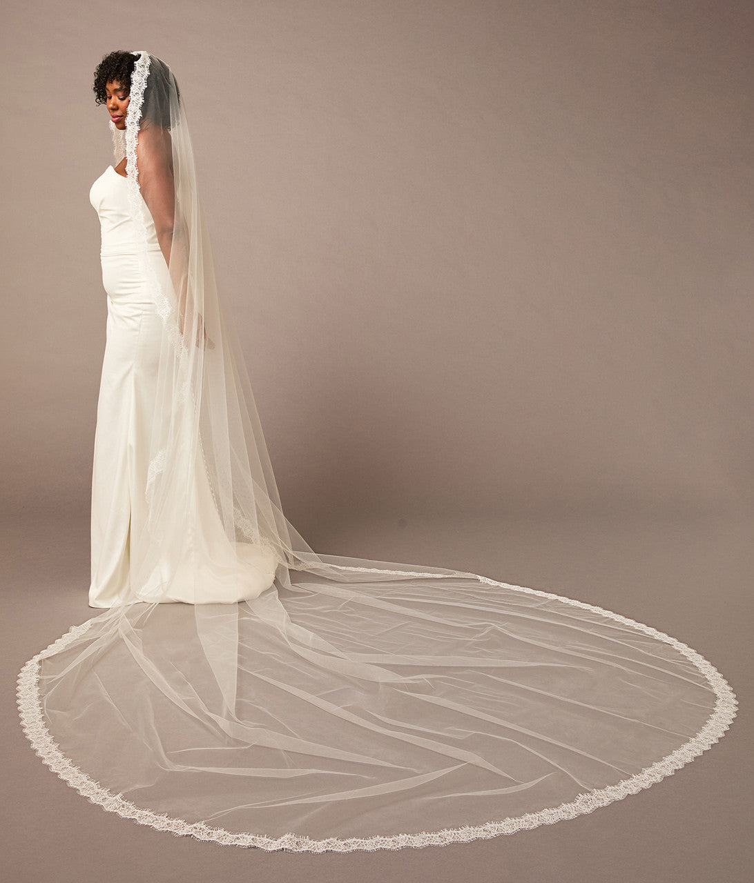 Double Eyelash Lace Cathedral Mantilla Veil Woman wearing a long white wedding veil against a plain background