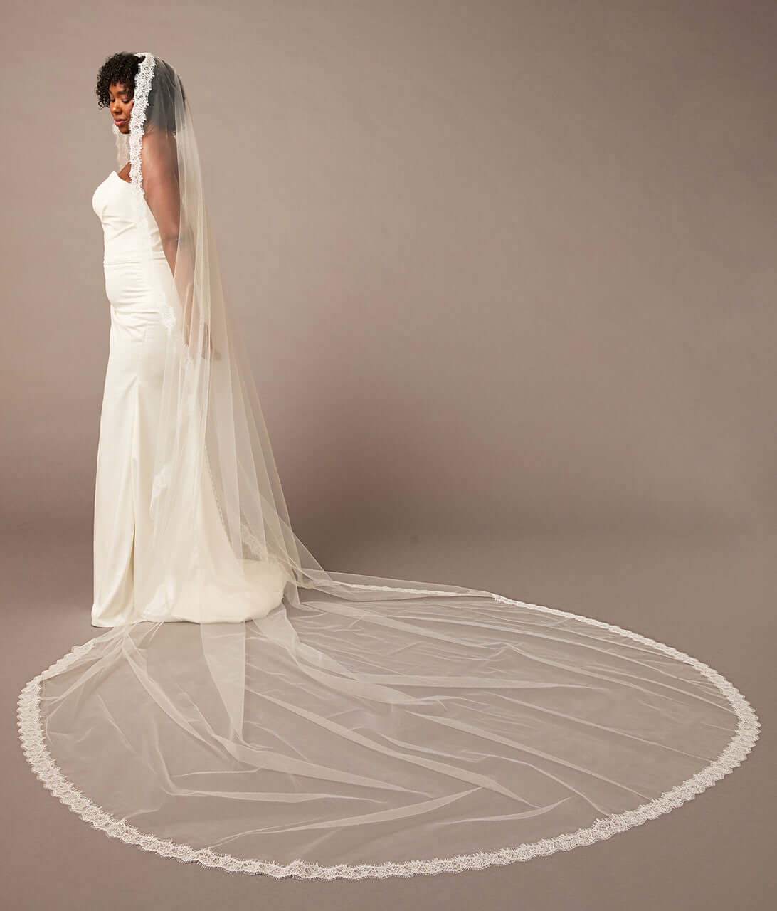 Double Eyelash Lace Cathedral Mantilla Veil Woman wearing a long white wedding veil against a plain background