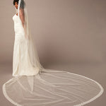 Double Eyelash Lace Cathedral Mantilla Veil Woman wearing a long white wedding veil against a plain background