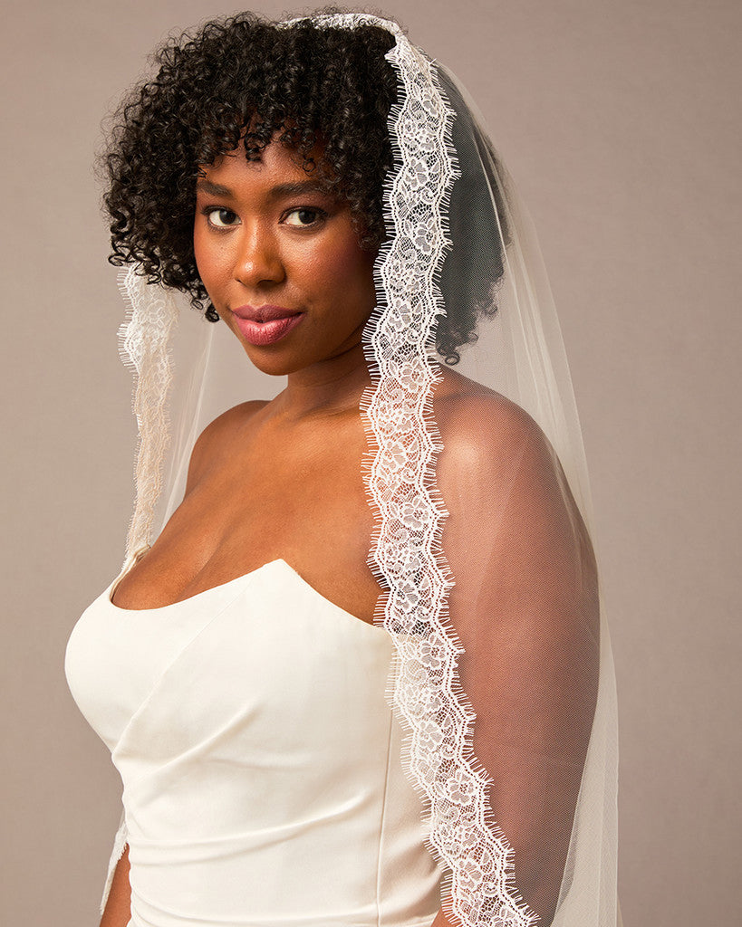 Double Eyelash Lace Cathedral Mantilla Veil Woman wearing a white wedding dress with a lace veil against a plain background