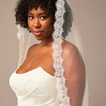 Double Eyelash Lace Cathedral Mantilla Veil Woman wearing a white wedding dress with a lace veil against a plain background