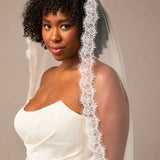 Double Eyelash Lace Cathedral Mantilla Veil Woman wearing a white wedding dress with a lace veil against a plain background