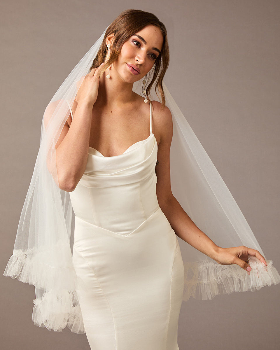 Fingertip Veil of Luxe Tulle with Ruffle Edge Woman wearing a wedding dress with a veil against a neutral background