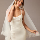 Fingertip Veil of Luxe Tulle with Ruffle Edge Woman wearing a wedding dress with a veil against a neutral background