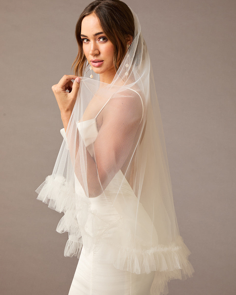 Fingertip Veil of Luxe Tulle with Ruffle Edge Woman wearing a wedding dress with a veil against a plain background