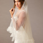 Fingertip Veil of Luxe Tulle with Ruffle Edge Woman wearing a wedding dress with a veil against a plain background