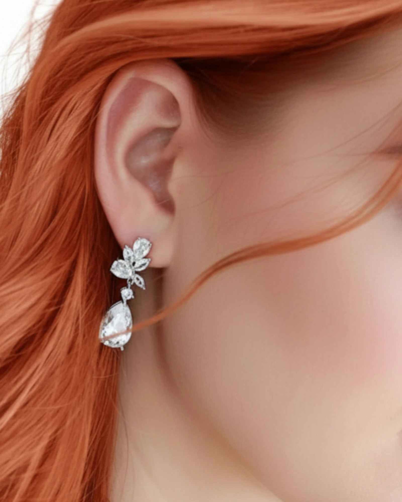 Close-up of a woman wearing a silver earring with red hair CZ Bridal earrings from Cassandra Lynne