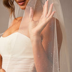 Fingertip Veil with Raindrop Scatter Woman wearing a wedding dress with a sheer veil against a neutral background