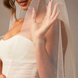 Fingertip Veil with Raindrop Scatter Woman wearing a wedding dress with a sheer veil against a neutral background