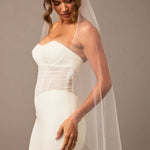 Fingertip Veil with Raindrop Scatter Woman wearing a strapless wedding dress with a sheer veil against a plain background
