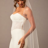Fingertip Veil with Raindrop Scatter Woman wearing a strapless wedding dress with a sheer veil against a plain background