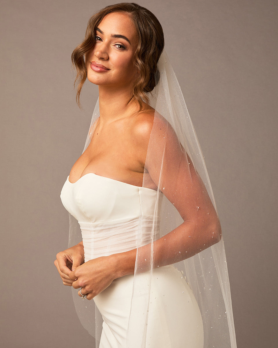 Fingertip Veil with Raindrop Scatter Woman wearing a strapless dress with a veil against a plain background